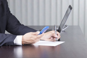 Obraz na płótnie Canvas businessman writing and holding smart phone