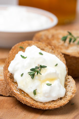 toasts with goat cheese, honey and thyme on wooden board