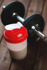 Close-up of a shaker with protein and a dumbbell
