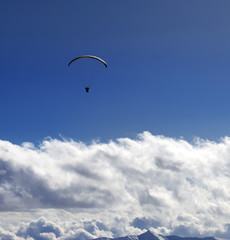 Silhouette of paraglider and blue sun sky