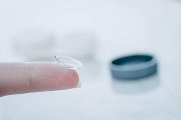 contact lens on finger with case in background