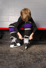 Boy Tying Hockey Skates in Dressing Room © Lorraine Swanson