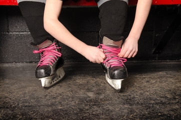 Fototapeta premium A Girl Tying Ice Hockey Skates in Dressing Room