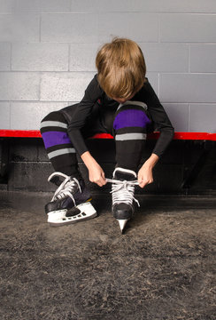 Boy Tying Hockey Skates in Dressing Room