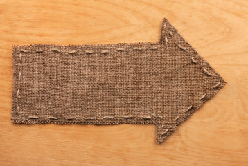 Arrow of burlap  lies on wooden  background