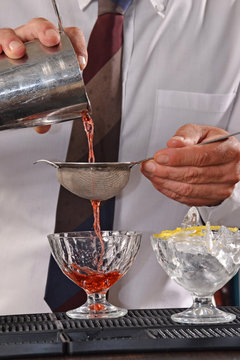 Barman preparando un coctel, colando bebida.