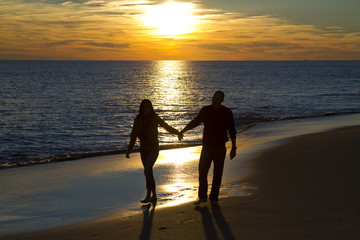 Couple walking on the oak island north carolina beach at sunset