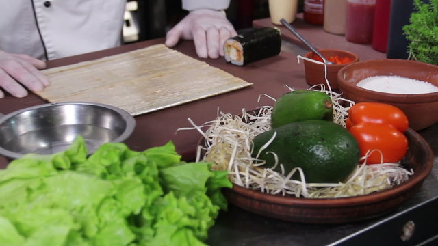 Cook ready to prepare sushi rolls, fresh vegetables on table