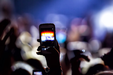 People taking photographs with touch smart phone during a music