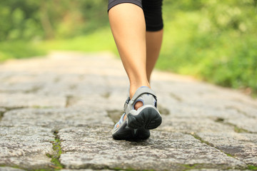 young fitness woman hiker legs walking on forest trail 