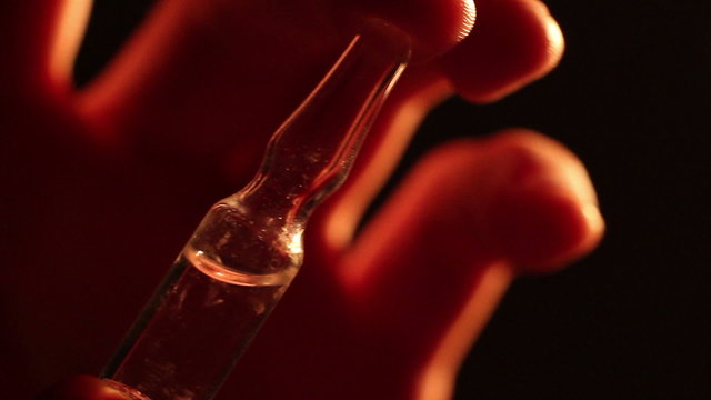Hand holding medical ampoule, drug addiction, medical treatment