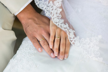 Hands with rings against wedding dress