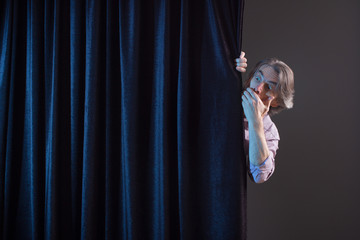 Scared man hiding behind a curtain.