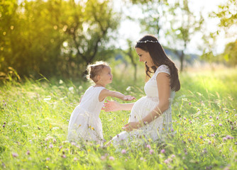 Pregnant mother with her little daughter in nature