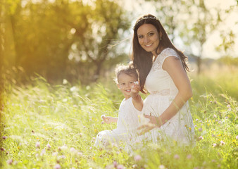 Pregnant mother with her little daughter in nature