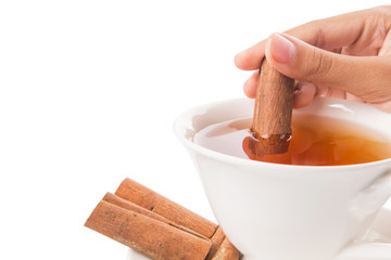 Female hand with a cup of tea and cinnamon stick