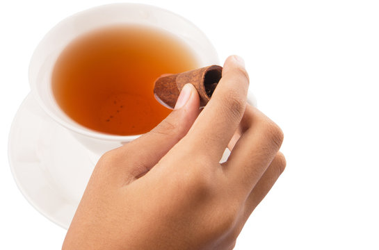 Female hand with a cup of tea and cinnamon stick