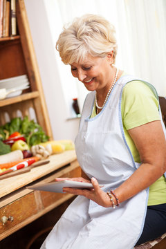 Senior Woman Using Tablet In Her Kitchen