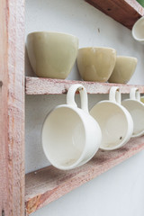 Fototapeta na wymiar White coffee cup hanging on wooden shelf