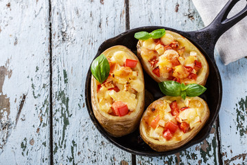 Stuffed potatoes with cheese and tomatoes in a pan