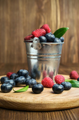 raspberries and blueberries in a small  bucket