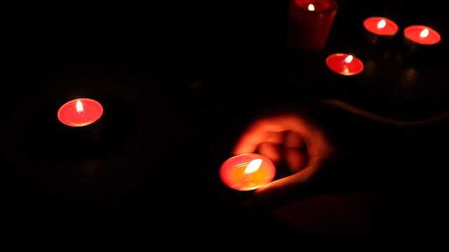 female hands put red candles with wax in semicircle, small light
