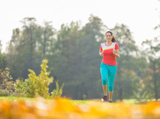 Young brunette woman running in park.