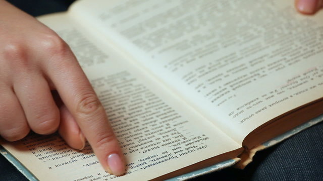 female hand shatters pages and show text of old book closeup