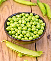 Green peas in brown bowl on board