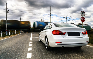 Luxury white car waiting at the railway crossing