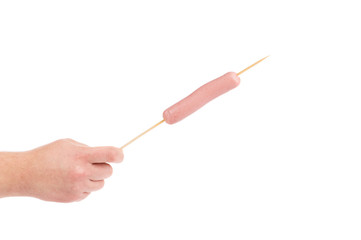 Hand holds sausage on stick