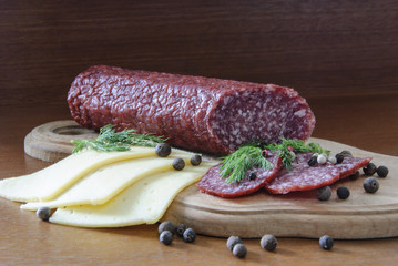 cheese sausage spices on a wooden board and a dark background