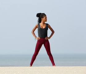Young black woman standing at beach with hand on hips