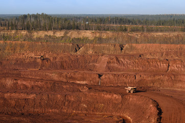 View to an open mine wall and few yellow tip-trucks