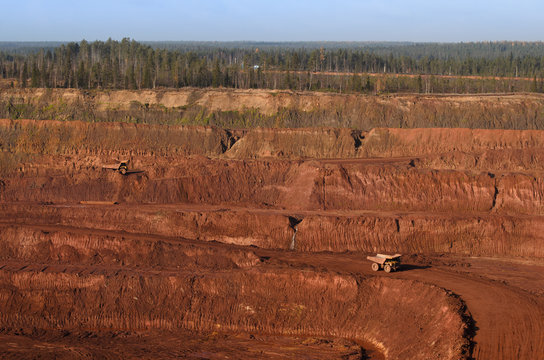 View to an open mine wall and few yellow tip-trucks