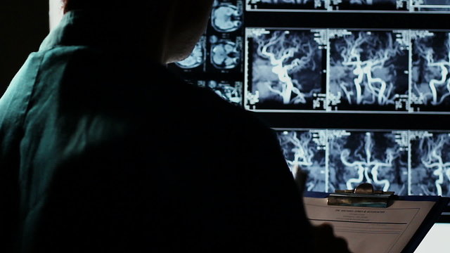 Doctor studying X-ray images human body, writing down diagnosis