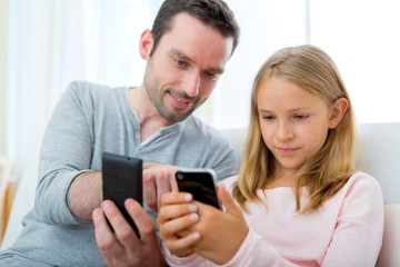 Father and his blond daughter using mobile