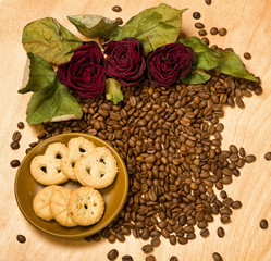 dry red roses and cookies on coffee seeds and wooden background