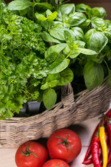 Different fresh herbs in basket on wooden background