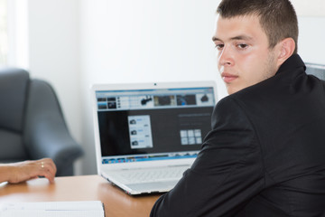 Young Businessman with Laptop Thinking Something