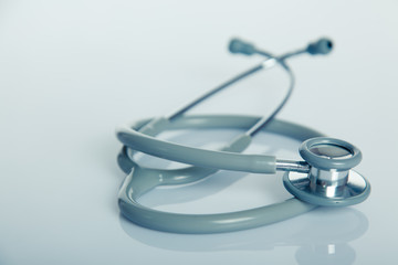 Gray stethoscope on white glossy table