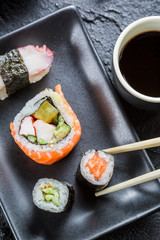 Sushi on black ceramic eaten with chopsticks