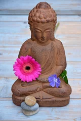 Gardinen Boeddha beeld op houten ondergrond met bloemen en Zen stenen © trinetuzun