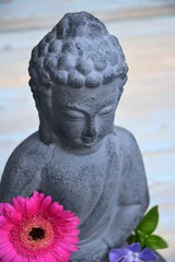 Schilderijen op glas Close-up van Boeddhabeeld met bloemen © trinetuzun