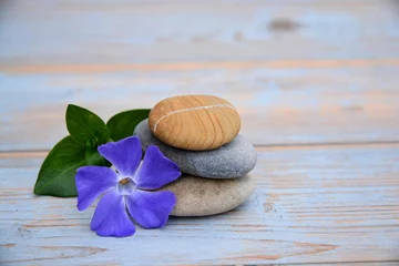 Foto op Plexiglas Drie Zen stenen op oud hout met paarse bloem © trinetuzun