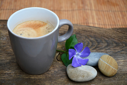 Koffie met drie zen stenen op bruin oud houd met paarse bloem