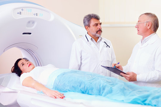 two doctors preparing patient to CT scanner procedure