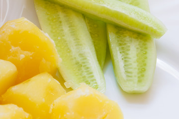 Cooked potatoes and fresh cucumber on plate.