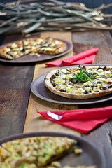 Three Pizzas on Rustic Wooden Table