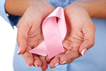 Woman with aids awareness pink ribbon in hands, close-up